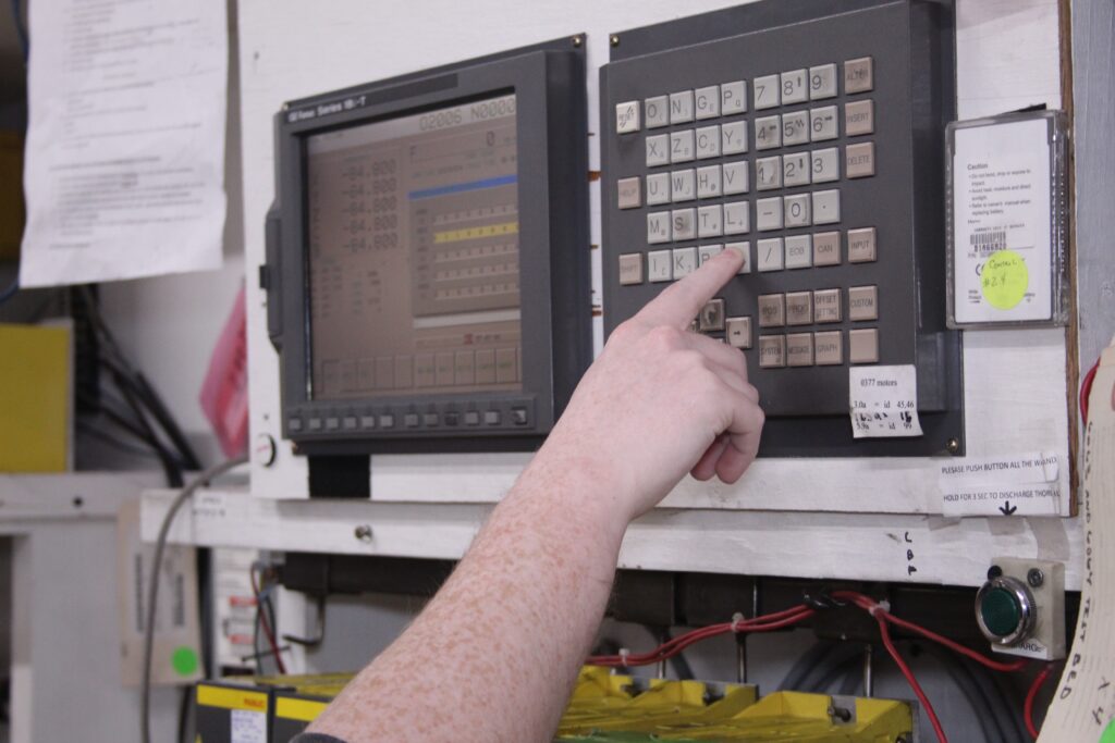 Fanuc technician operating CNC equipment in an industrial environment.